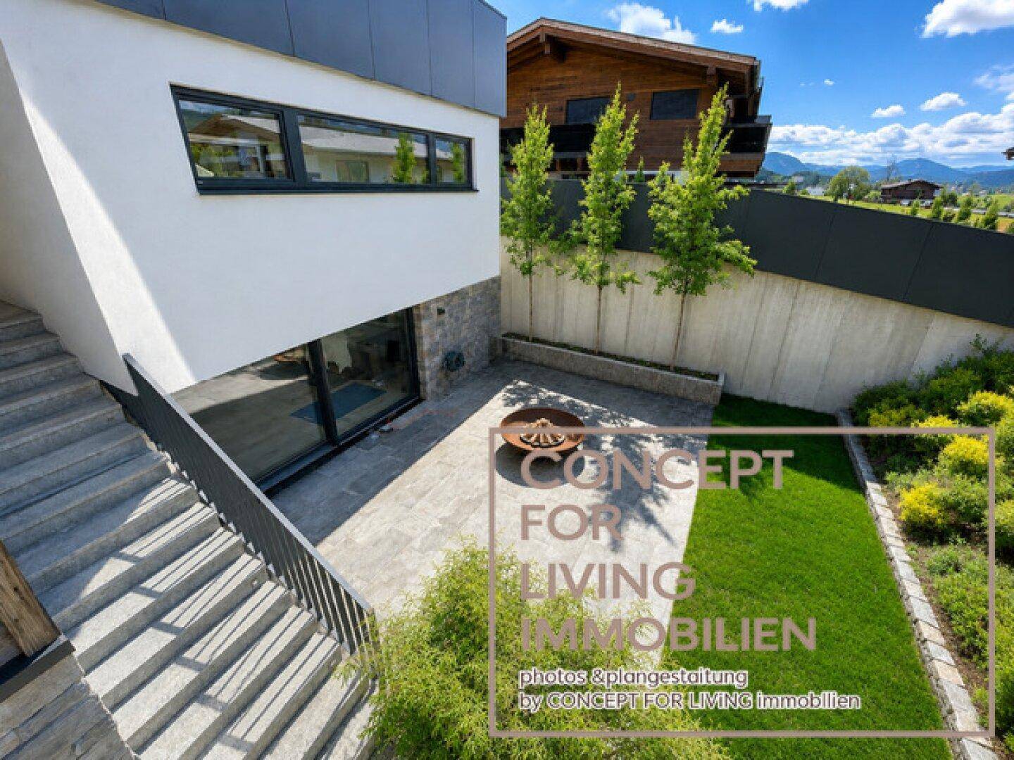 Elegantes Gebäude mit moderner Architektur, Steinfassade und einem Garten mit Feuerstelle.