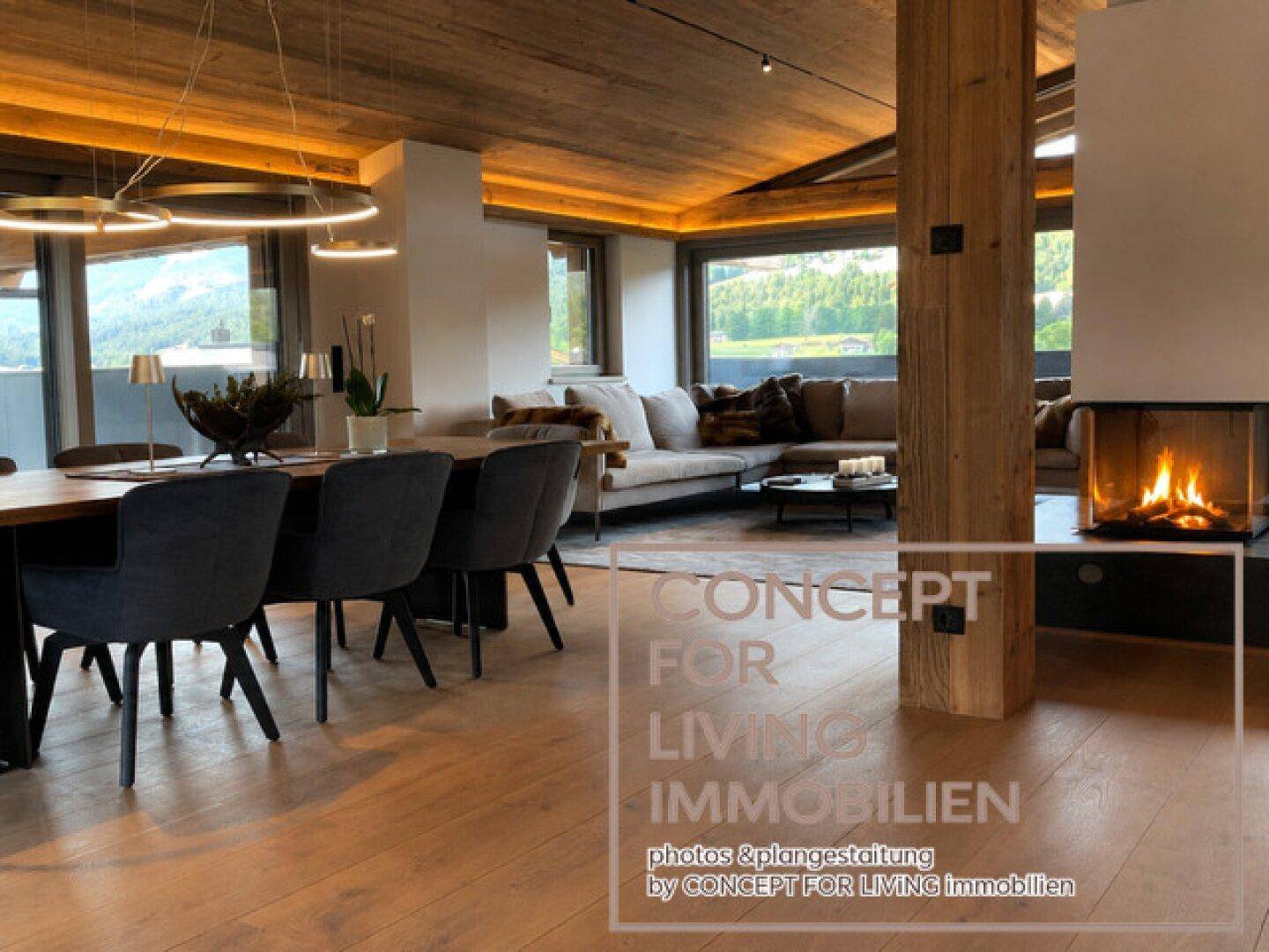 Geräumiger Wohn-Essbereich mit Holzboden, modernem Kamin und Zugang zu großen Fenstern.