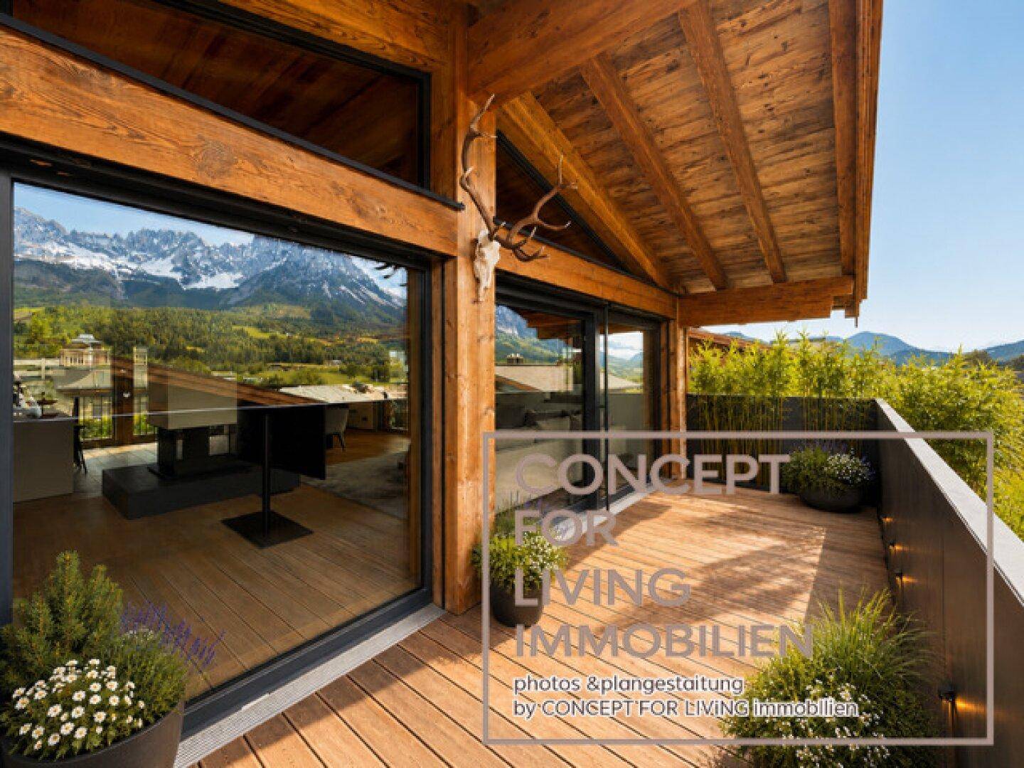Sonniger Balkon mit Holzboden, Pflanzen und beeindruckendem Bergblick, ideal zum Entspannen.