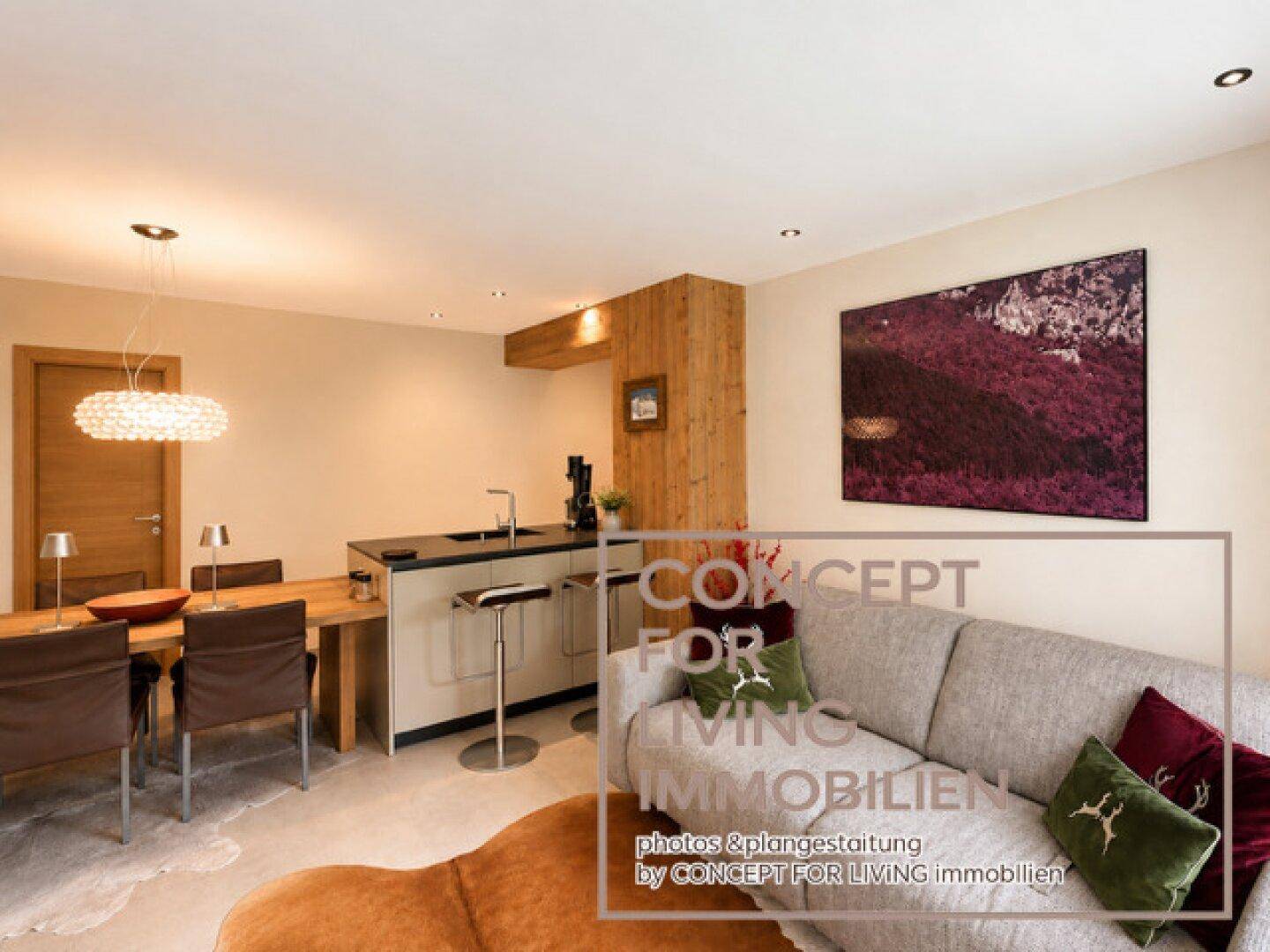 Offener Wohnbereich mit Sofa, Esstisch und Küchenzeile, ideal für geselliges Beisammensein.