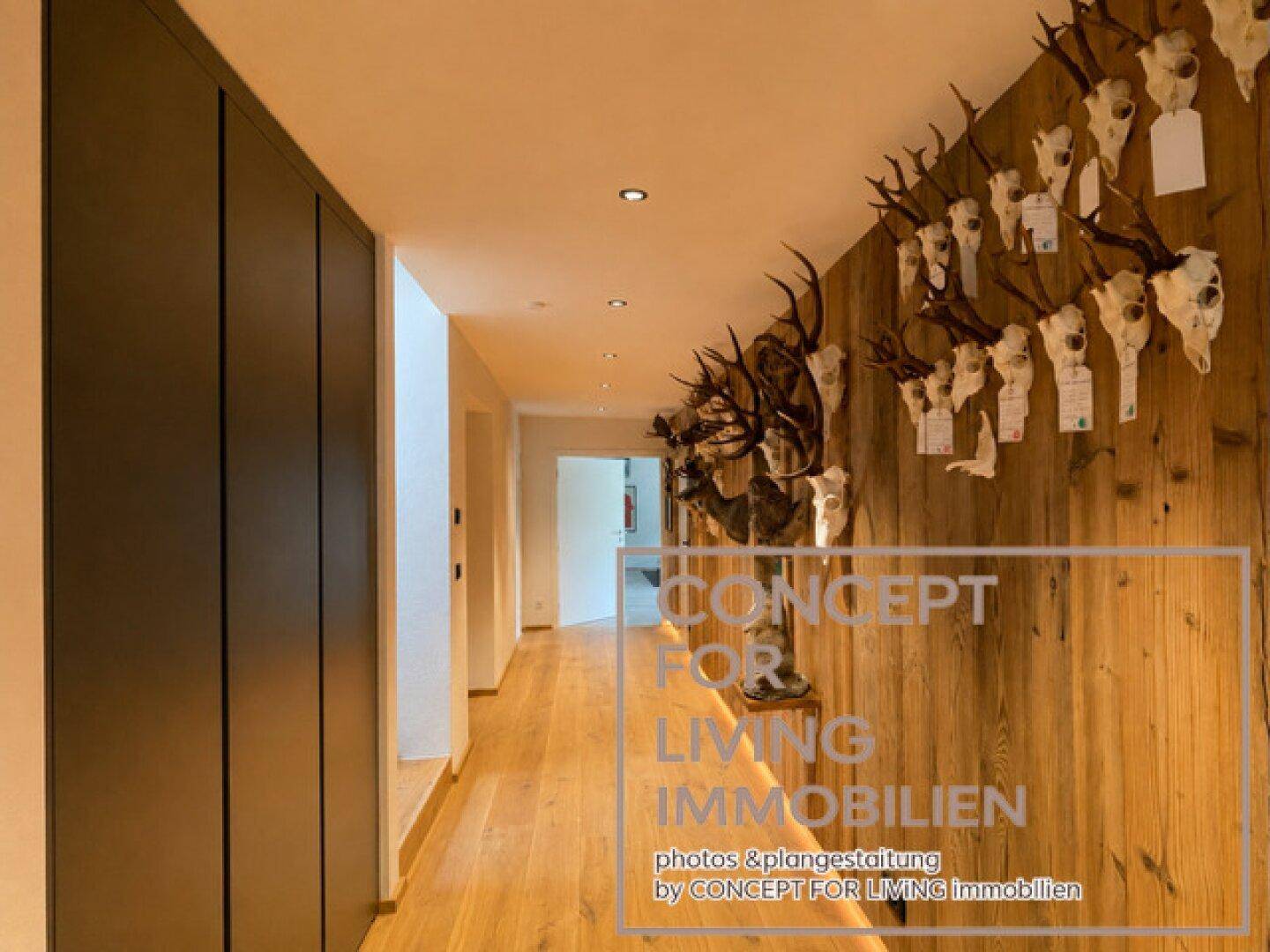 Langer Flur mit Holzwand und traditionellen Jagdtrophäen, die eine rustikale Atmosphäre schaffen.