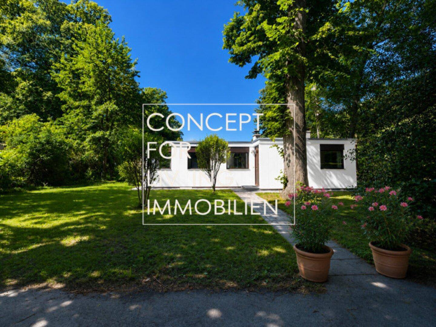 Vorderansicht eines modernen Hauses mit gepflastertem Weg, umgeben von einem grünen Rasen und hohen Bäumen.