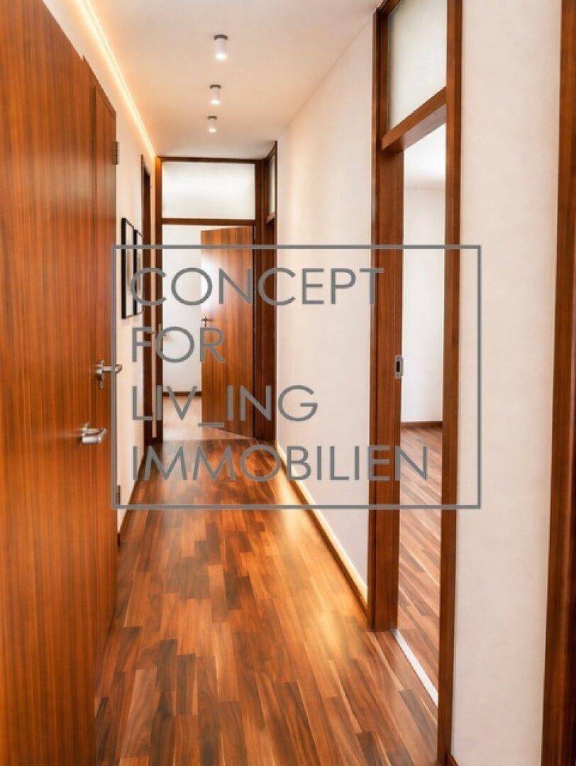 Langer Flur mit dunklem Holzboden, Holztüren und moderner Deckenbeleuchtung.