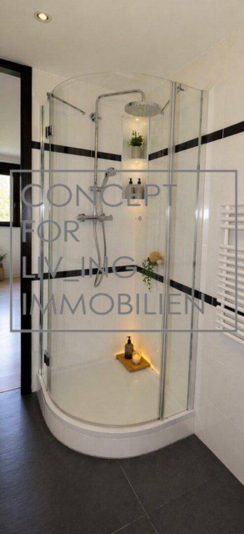 Modernes Badezimmer mit runder Duschkabine, dunklen Fliesen und weißer Wandgestaltung.