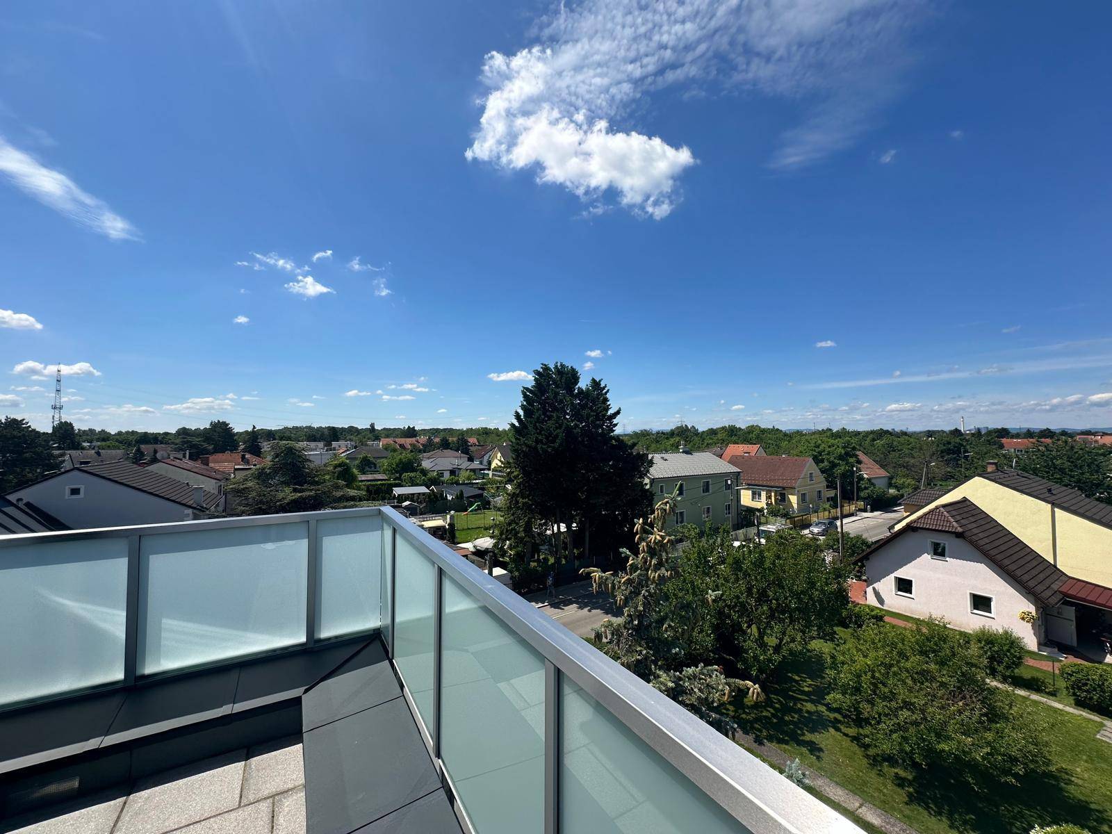 Weitblick über eine grüne Wohngegend von einer modernen Dachterrasse.