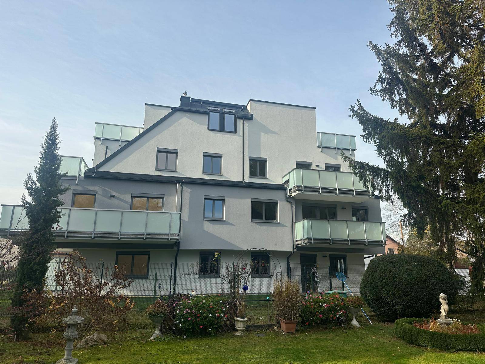 Modernes Wohngebäude mit mehreren Balkonen und einem weitläufigen, grünen Gartenbereich.