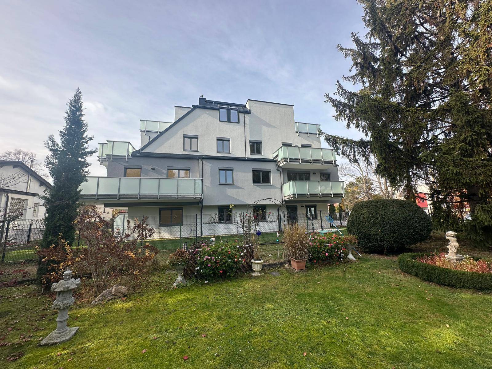 Modernes Wohngebäude mit mehreren Balkonen und einem großen, grünen Gartenbereich.