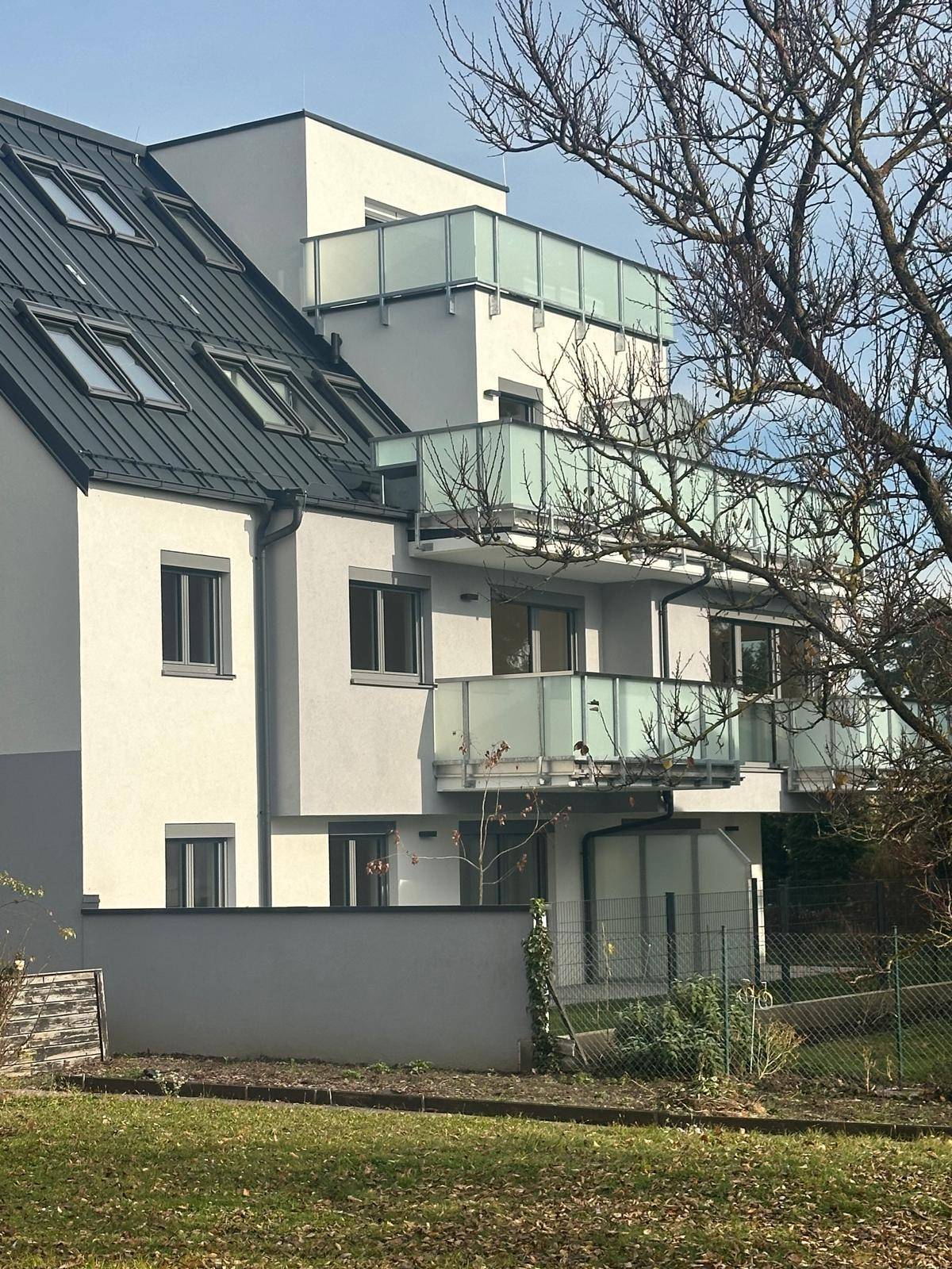 Detailansicht der modernen Fassade eines Wohnhauses mit Balkonen und Dachfenstern.