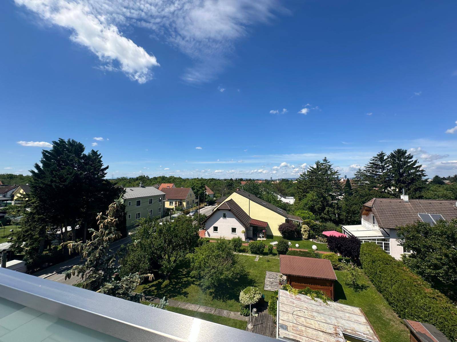 Weitläufiger Blick vom Balkon auf die grüne Landschaft und Einfamilienhäuser.