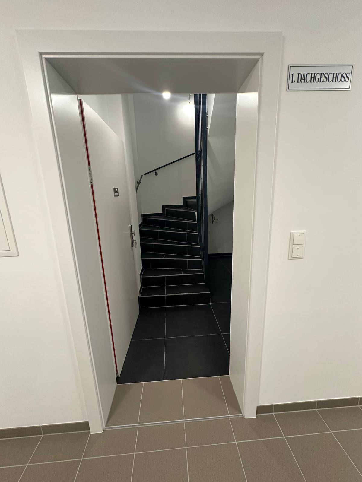 Eingangsbereich zum 1. Dachgeschoss mit moderner Treppe und Fliesenboden.