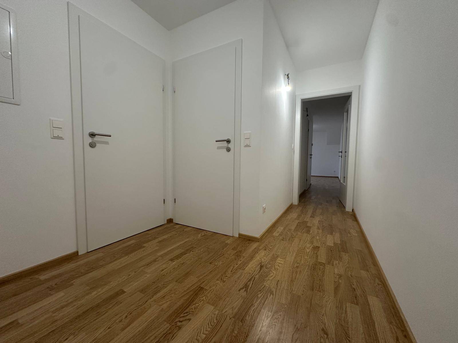 Langer Flur mit Holzboden und mehreren weißen Türen, die zu verschiedenen Zimmern führen.