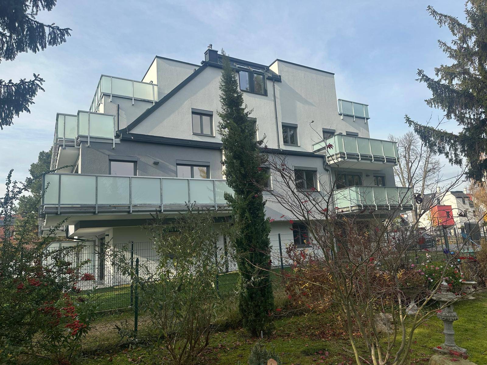 Rückansicht des modernen Wohnhauses mit gepflegtem Garten und Balkonen.