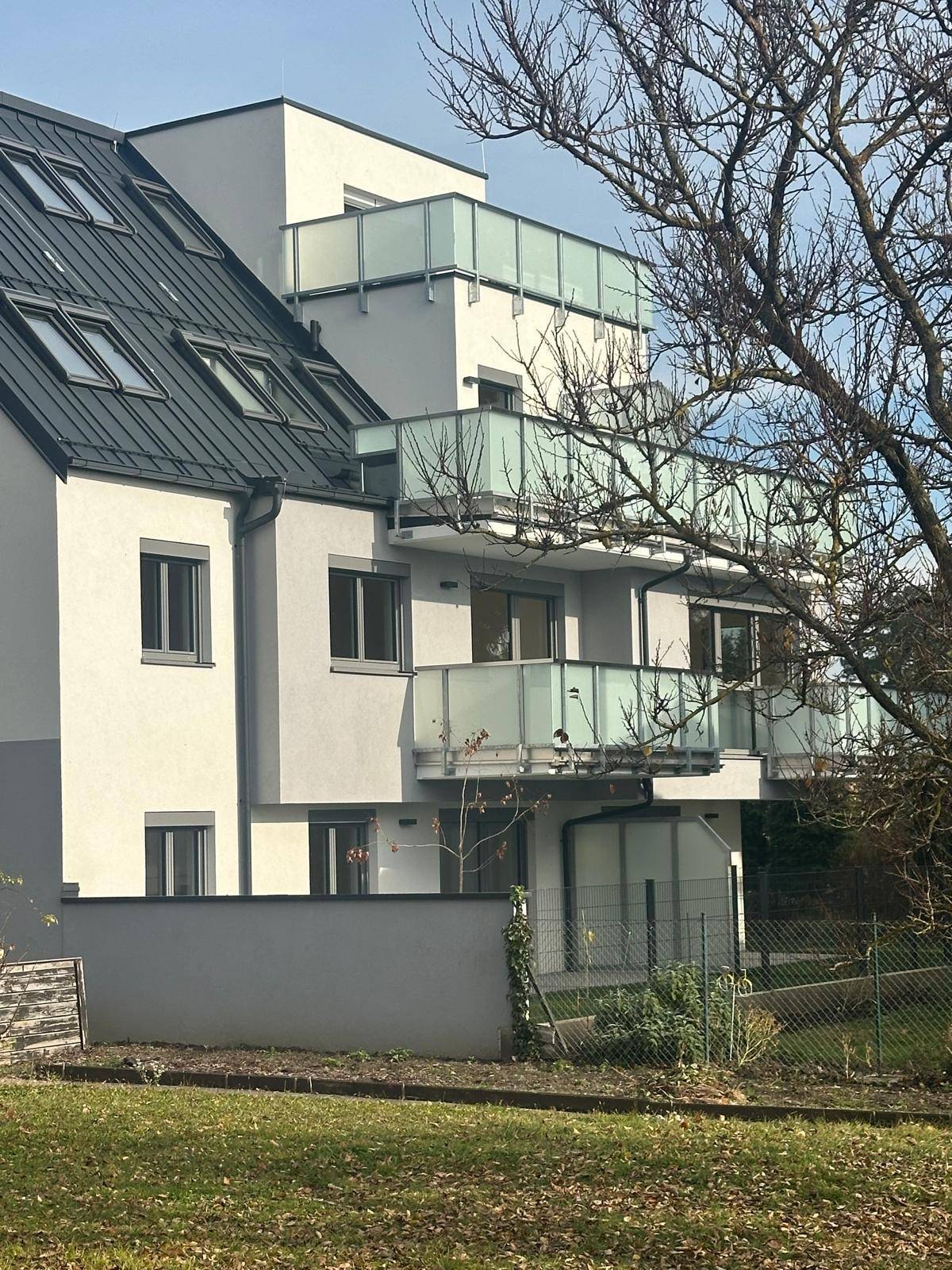 Seitenansicht des modernen Gebäudes mit mehreren Balkonen und Dachfenstern.