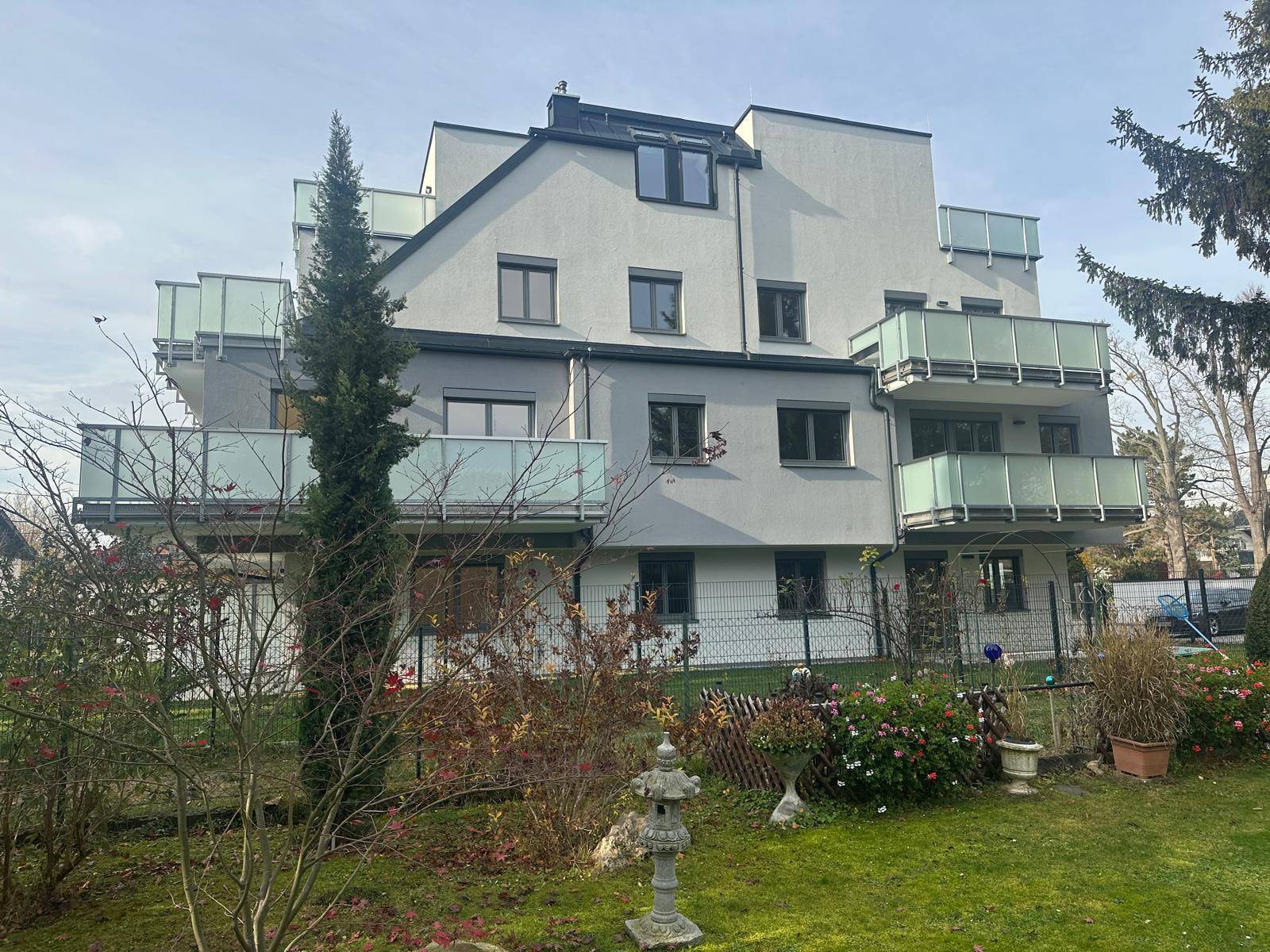 Ansicht des modernen Wohngebäudes mit mehreren Balkonen und einem grünen Garten.