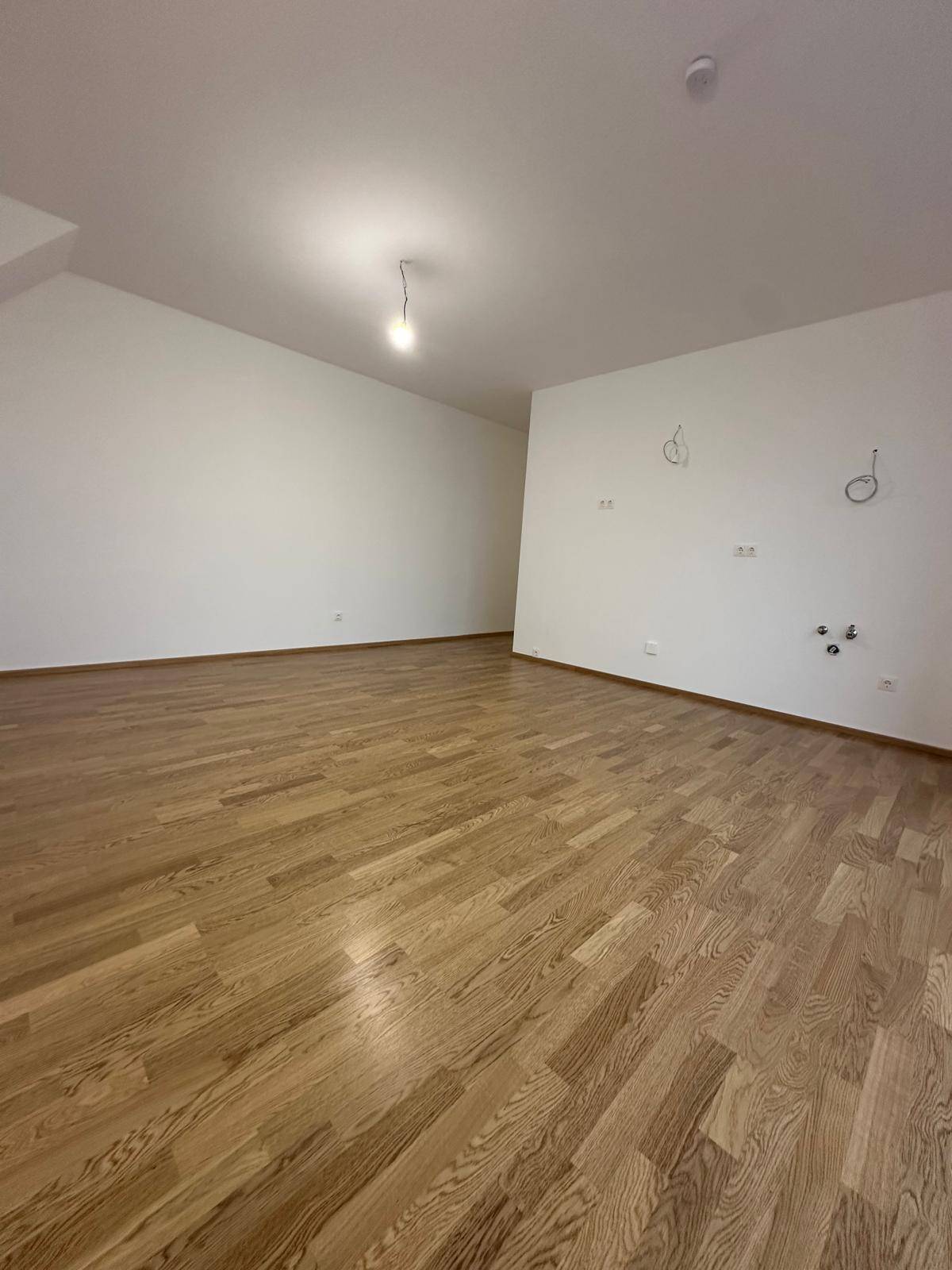 Geräumiger, leerer Raum mit hellem Holzboden und weißen Wänden, bereit für die Einrichtung.