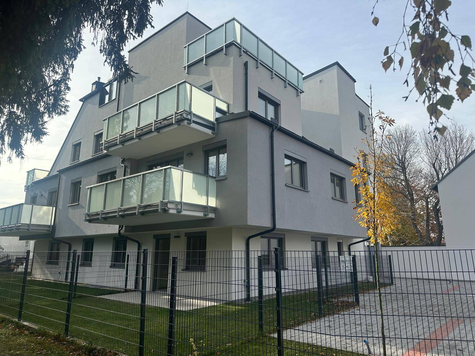 Moderne Architektur des Neubaus mit Balkonen und umzäuntem Grundstück.