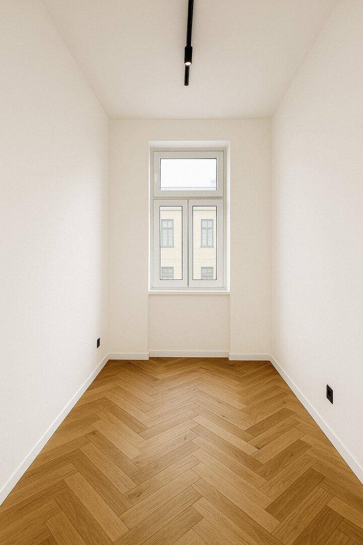 Schmaler Raum mit Fischgrätparkett und einem Fenster für Tageslicht.