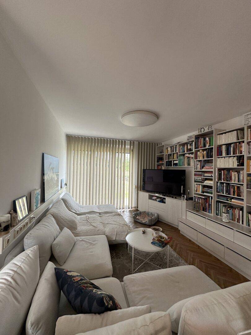 Helles Wohnzimmer mit großem Ecksofa, Bücherregalen und Parkettboden.
