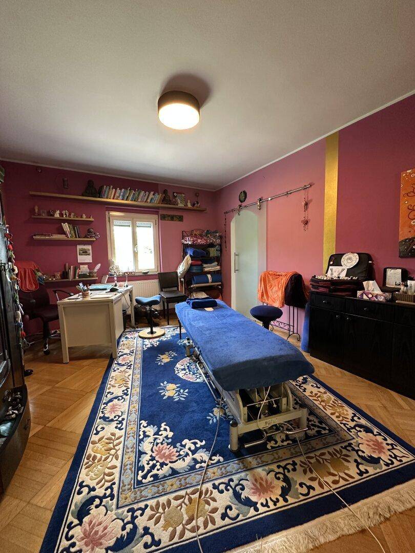 Farbig gestalteter Raum, der als Büro oder Therapiezimmer genutzt wird, mit Holzboden.