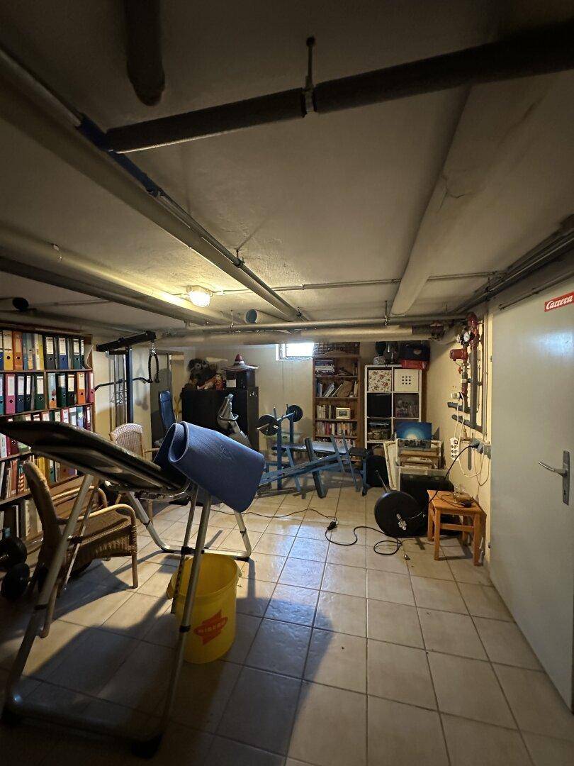 Kellerraum, der als Fitnessraum und Lagerbereich genutzt wird, mit Fliesenboden.