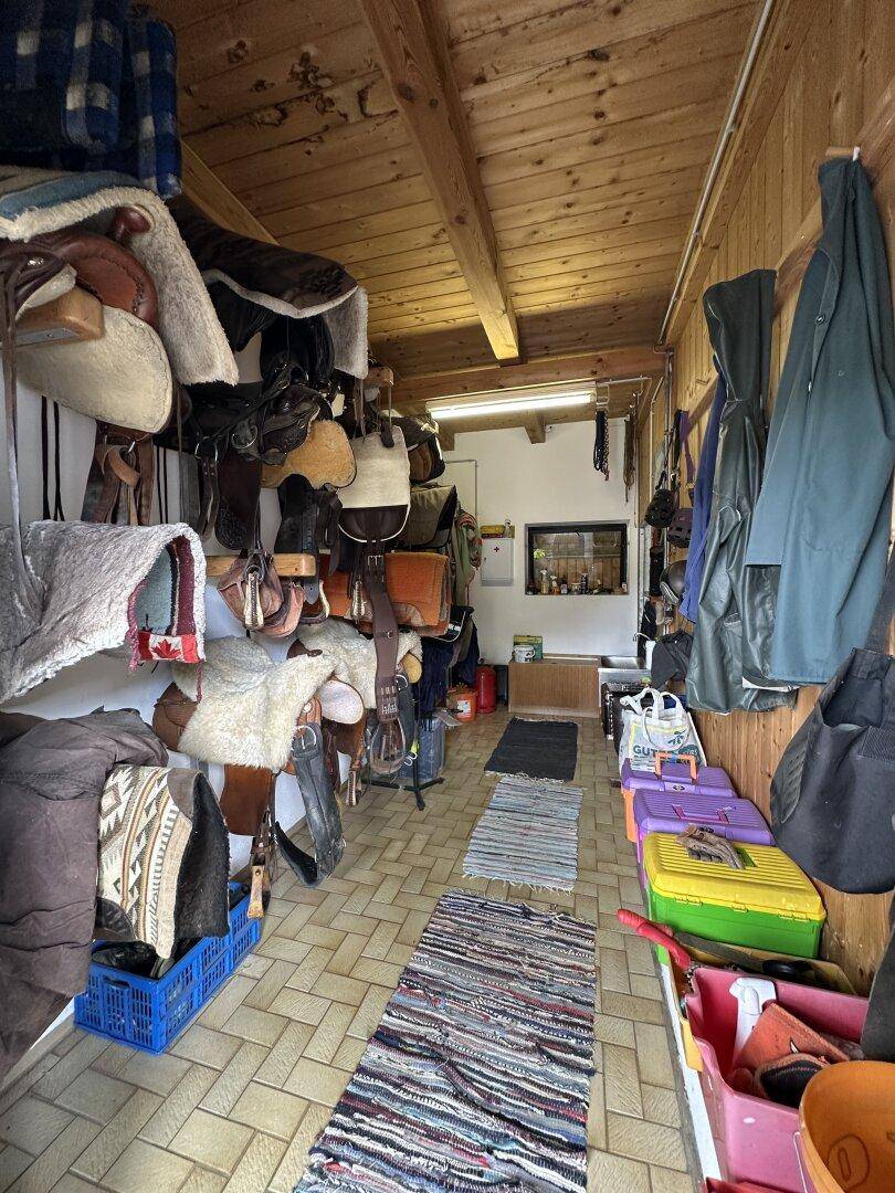 Lagerraum für Reitausrüstung mit Holzverkleidung und Fliesenboden.
