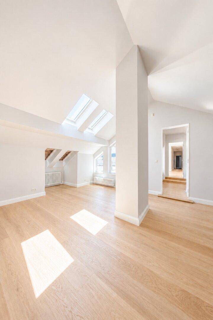 Heller Wohnbereich mit Holzboden, Dachschrägen und mehreren Dachfenstern für viel Licht.