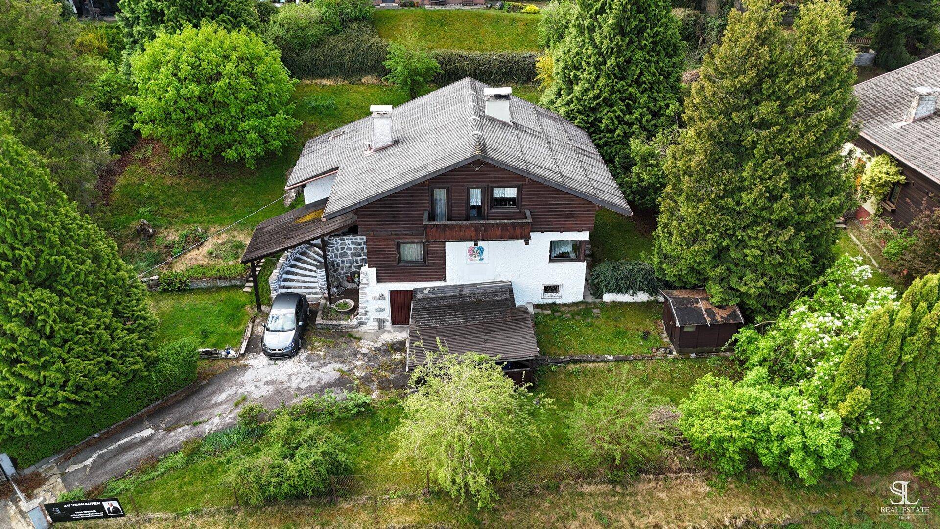 Luftaufnahme des Hauses mit Garten, Zufahrt und umliegender grüner Landschaft.