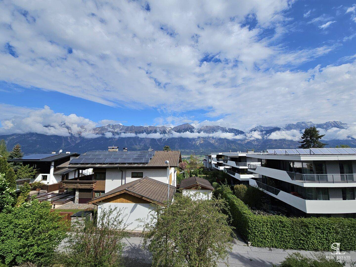 Weitblick auf die majestätische Bergkette und die umliegende Wohnbebauung unter blauem Himmel.