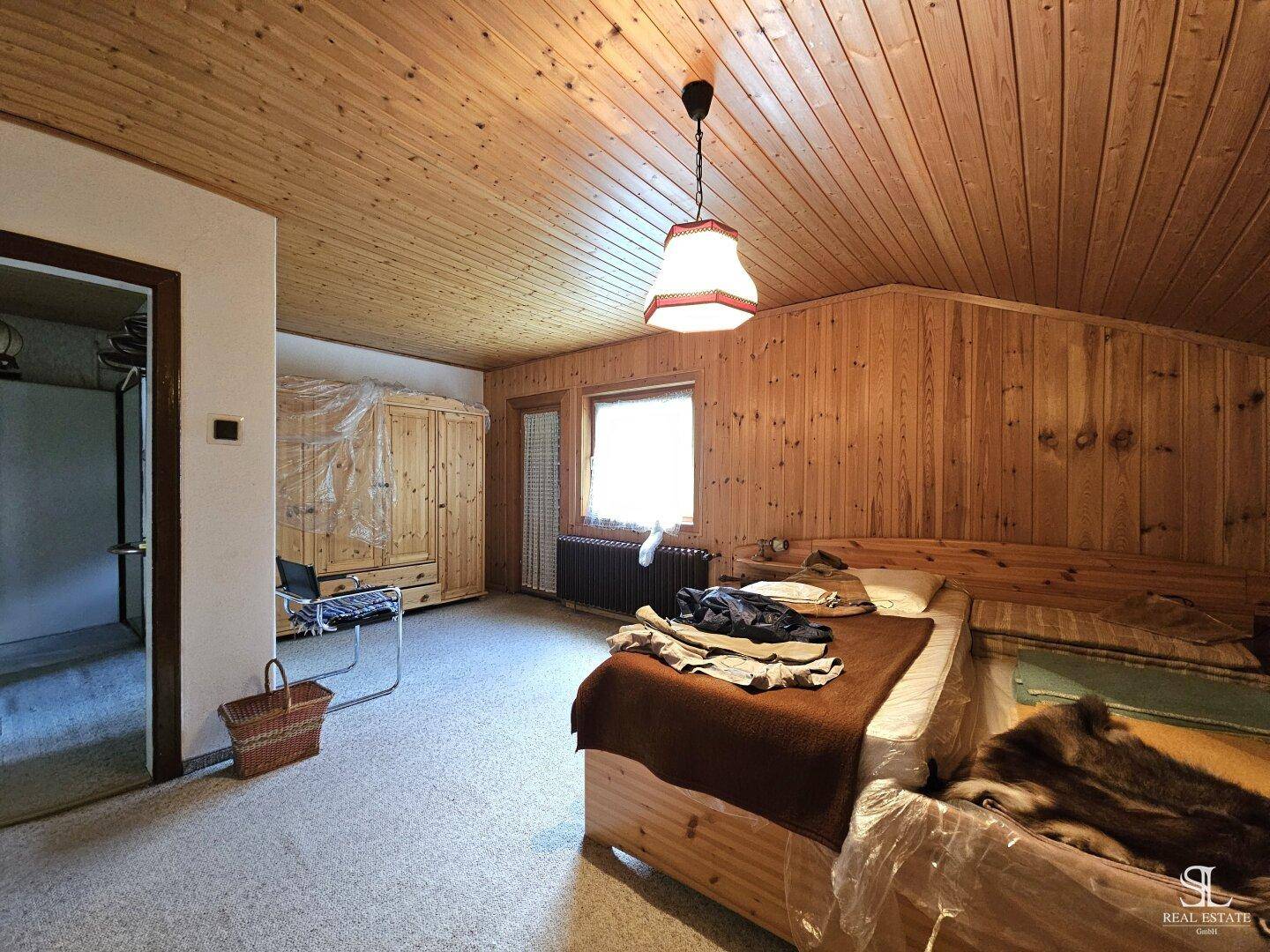 Schlafzimmer mit Holzvertäfelung, Teppichboden und einem Bett mit Holzrahmen.