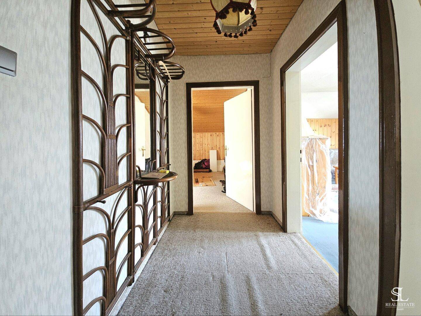 Langer Flur mit Teppichboden und Holzdecke, ausgestattet mit einer Garderobe.
