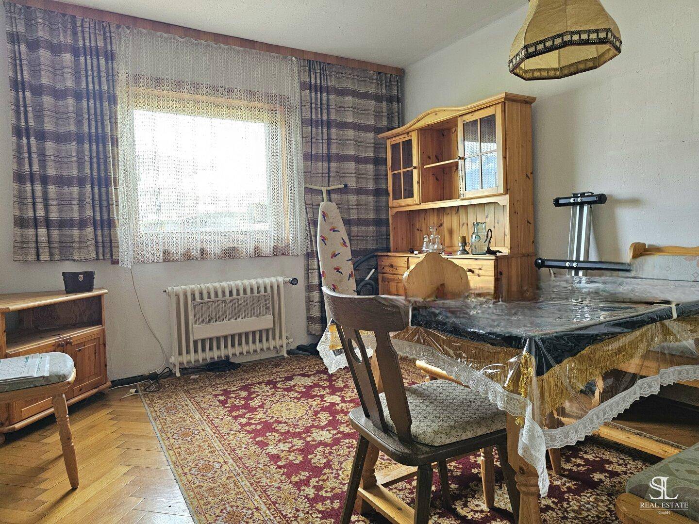 Esszimmer mit Holzboden, großem Fenster und traditionellen Möbeln.