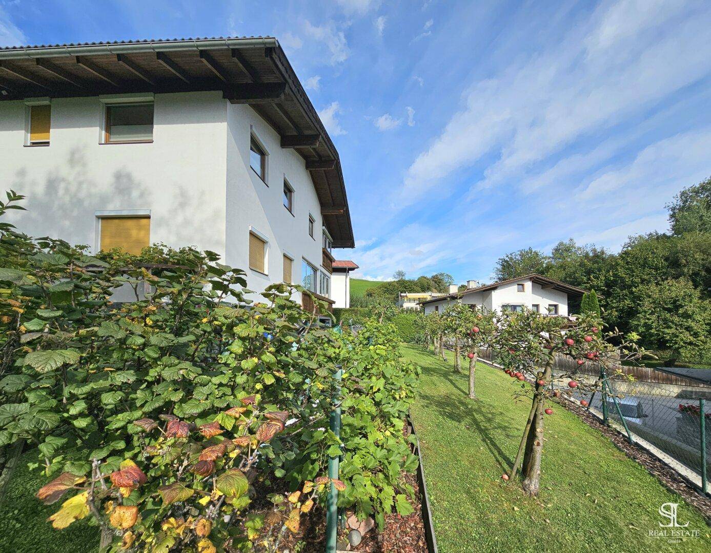 Gepflegter Gartenbereich mit Obstbäumen und Sträuchern, der zum Haus führt.