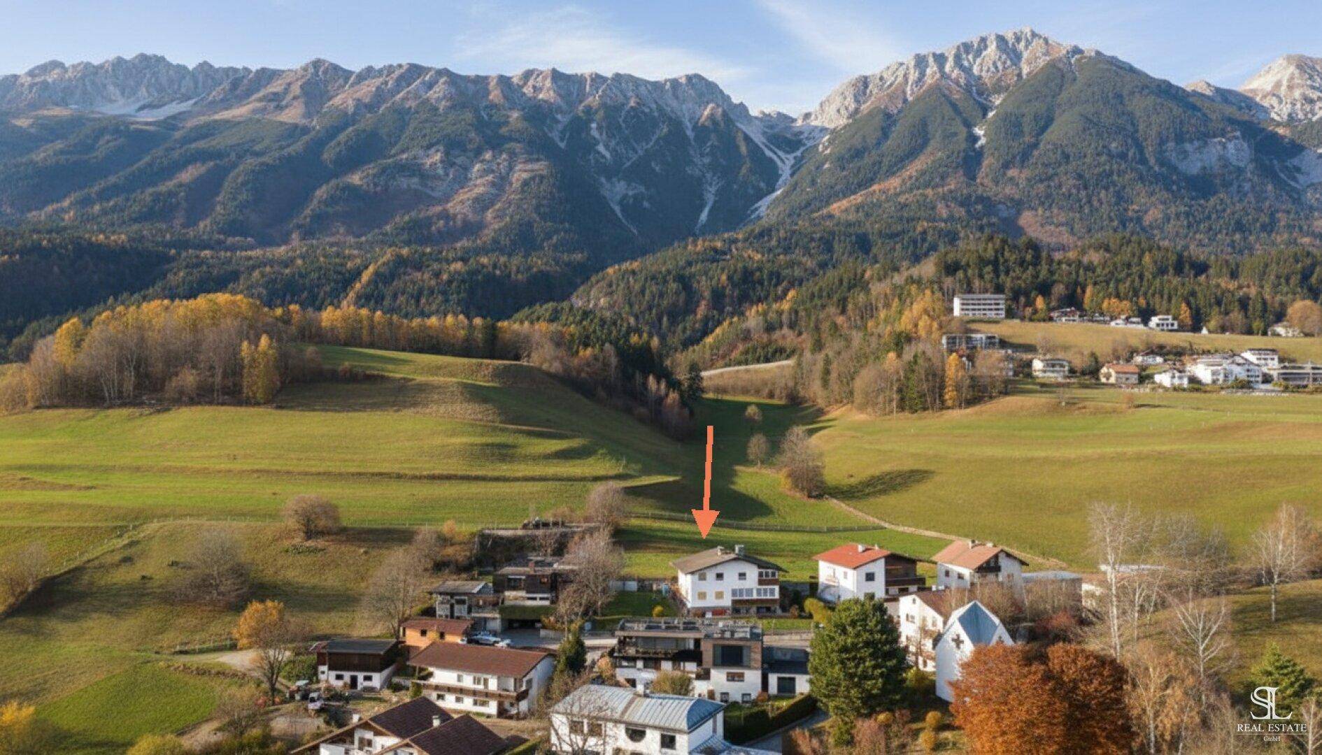 Übersichtliche Luftaufnahme des Hauses und der Nachbarschaft, umgeben von weitläufigen grünen Wiesen und Bergen.