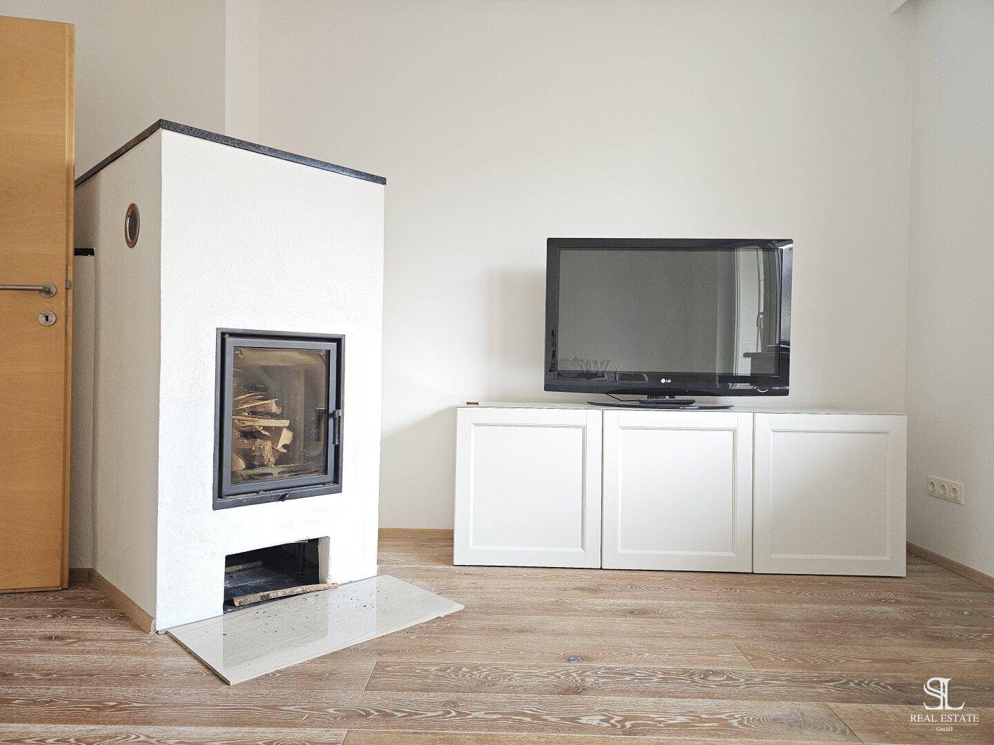 Moderner Kamin und Fernseher auf einem weißen Schrank im Wohnzimmer mit Holzboden.
