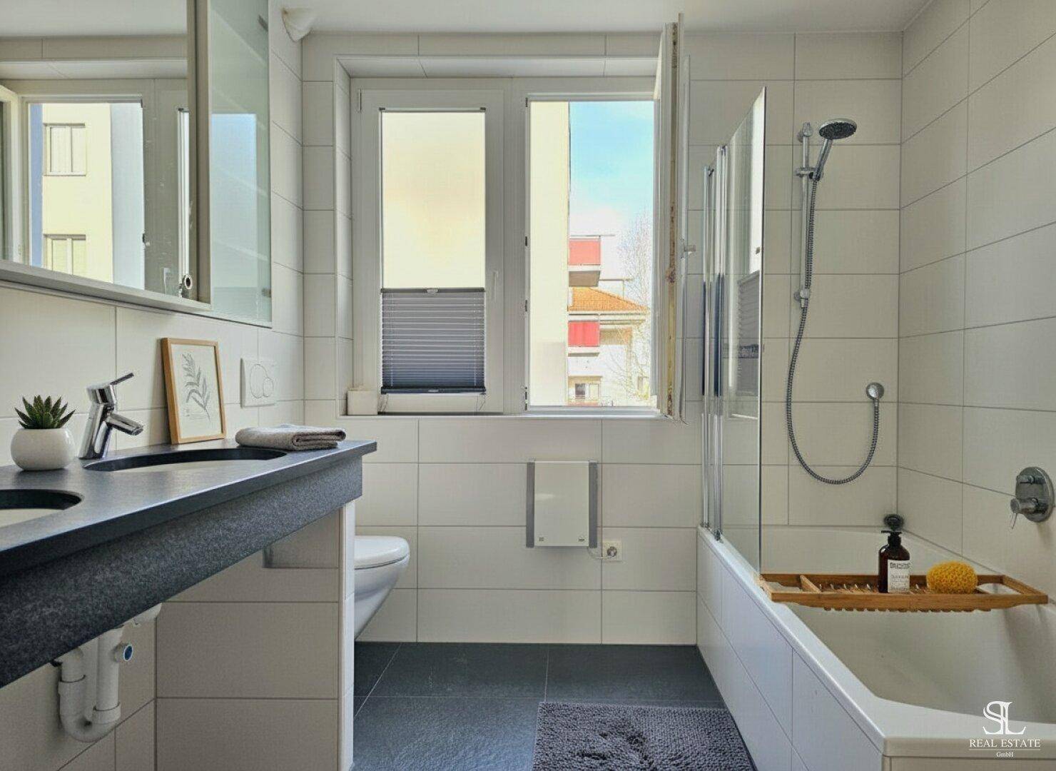 Modernes Badezimmer mit Badewanne, Dusche, Waschtisch, Toilette und Fenster.