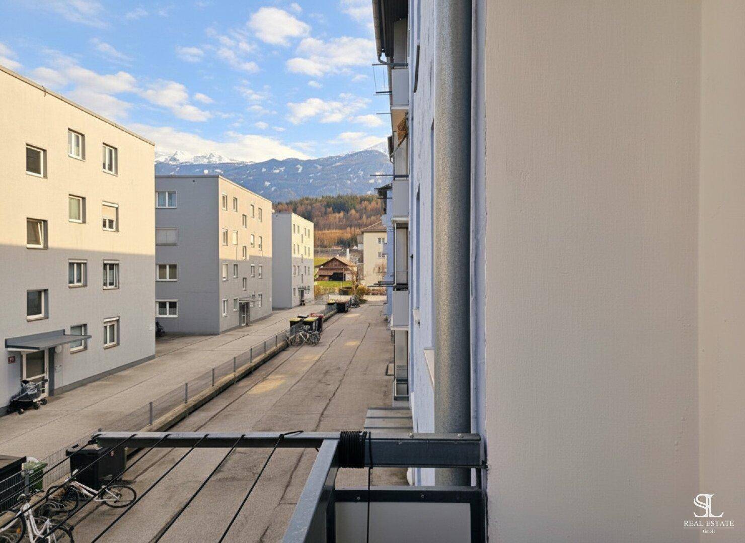 Ausblick vom Balkon auf moderne Wohngebäude und die entfernte Bergkulisse.