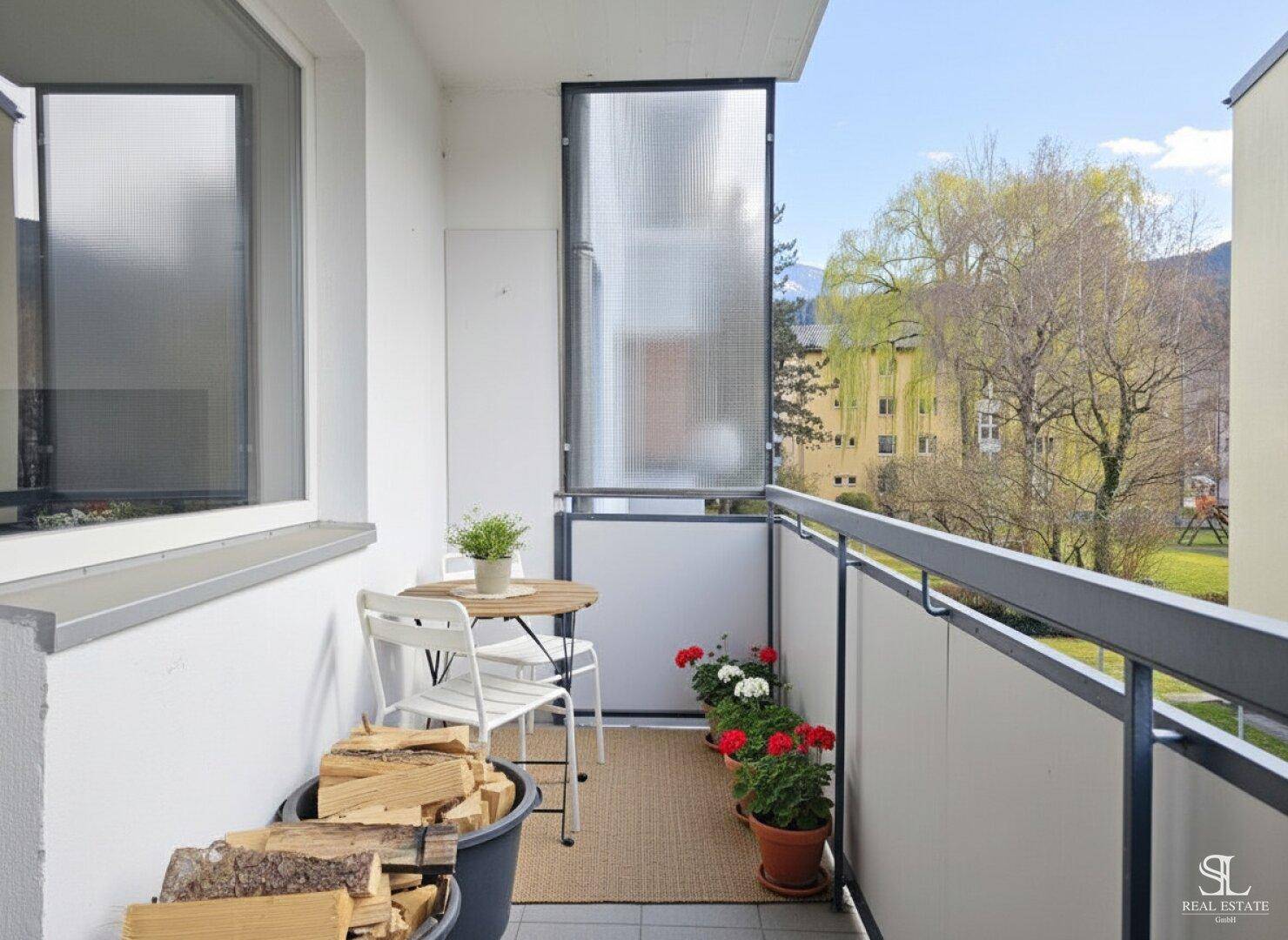 Gemütlicher Balkon mit Sitzgelegenheiten, Pflanzen und praktischem Stauraum für Brennholz.