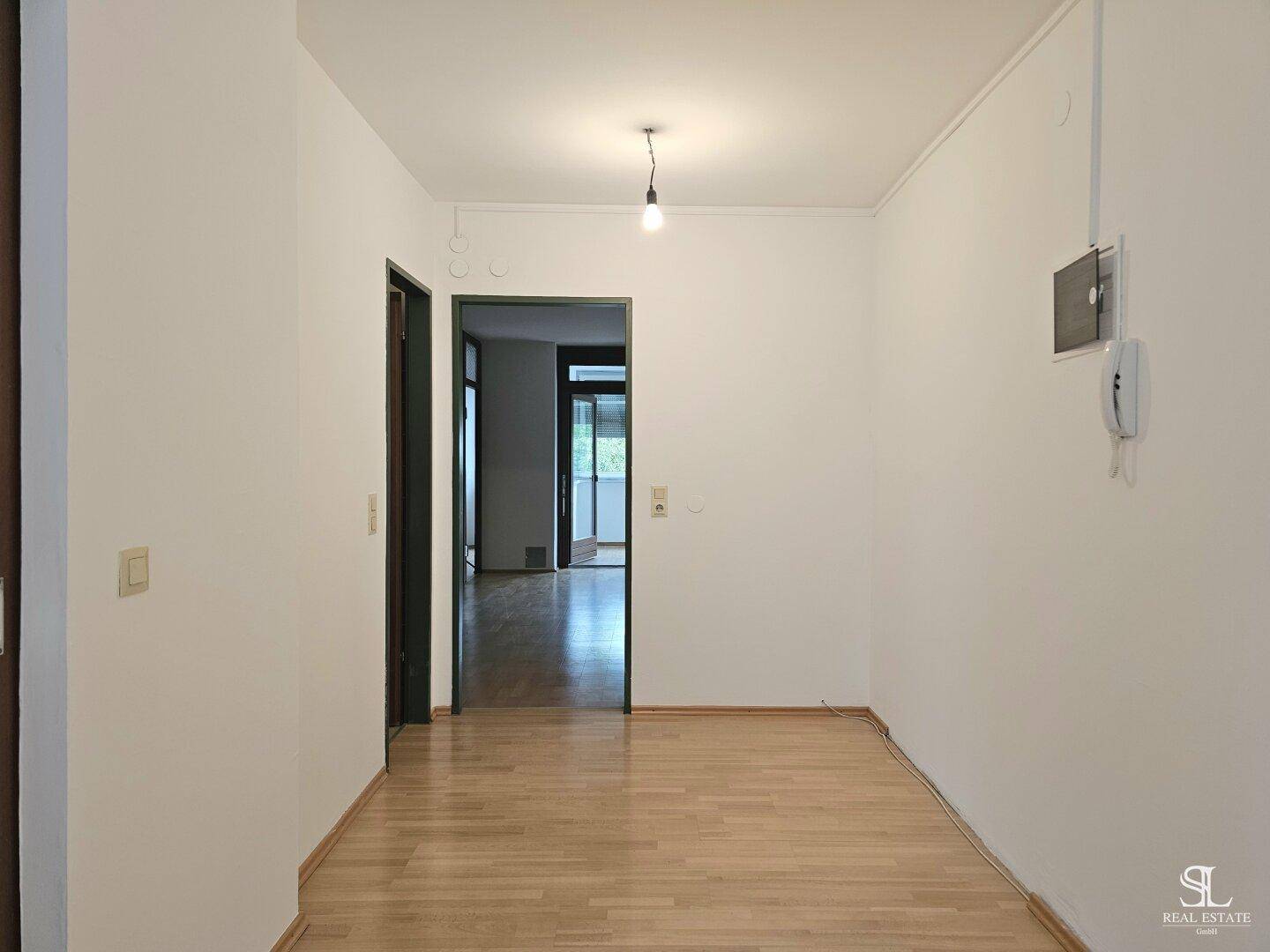 Heller Flur mit Holzboden und mehreren Türen, die zu den angrenzenden Räumen führen.