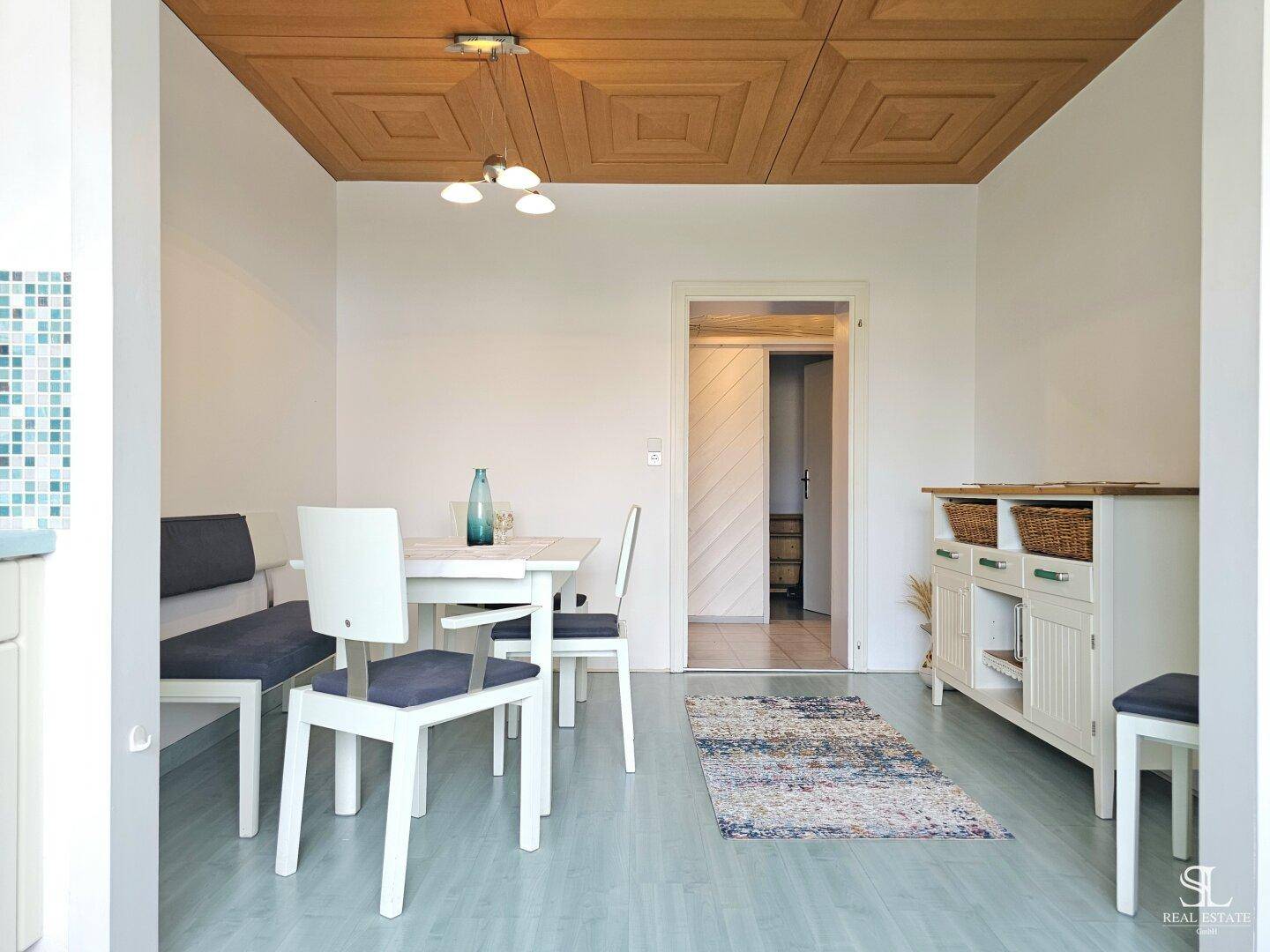 Essbereich mit Holztischdecke, weißem Sideboard und Holzakzenten an der Decke.