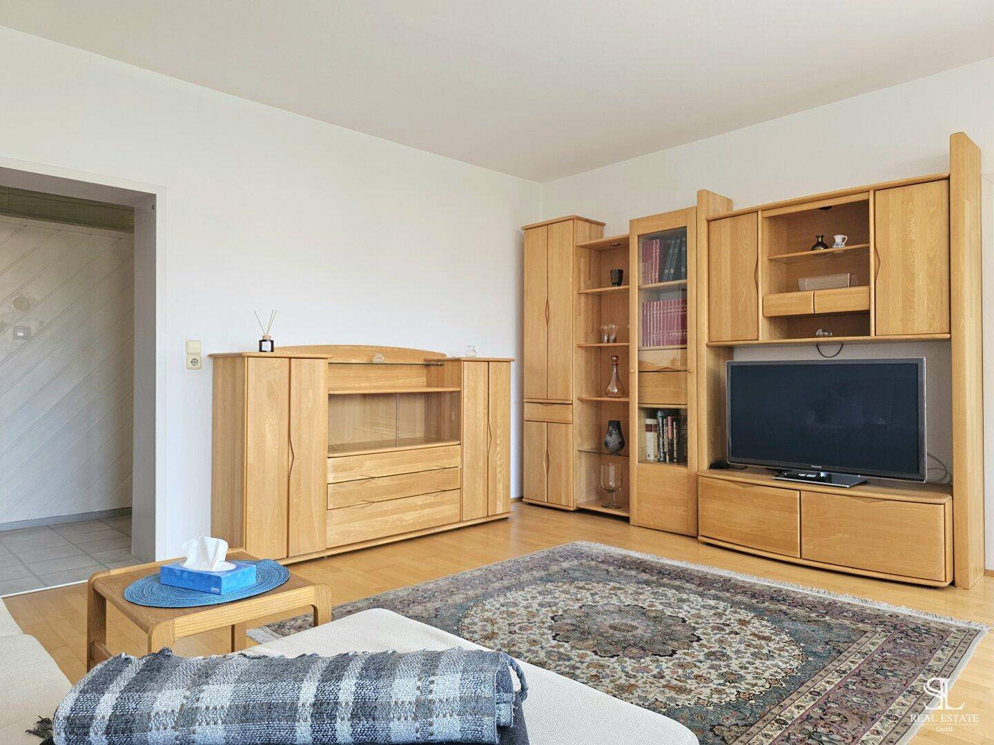 Wohnzimmer mit Holzmöbeln, Teppich und einem Fernseher, der eine gemütliche Atmosphäre schafft.