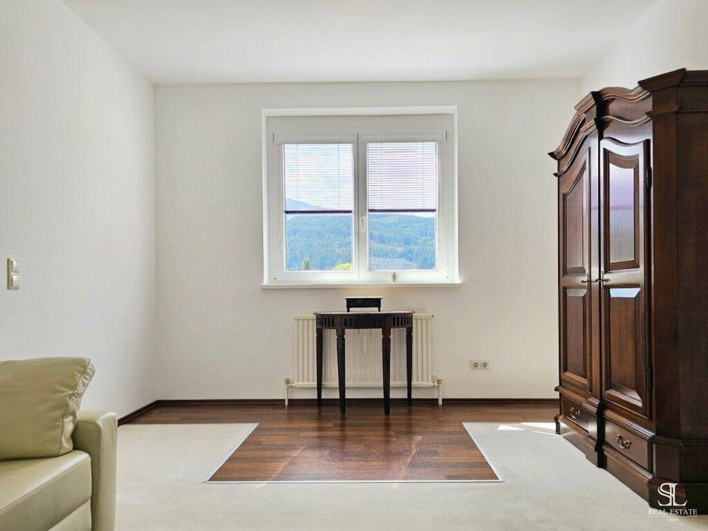Geräumiger Raum mit Fenster zum Bergpanorama, großem Holzschrank und Teppichboden.