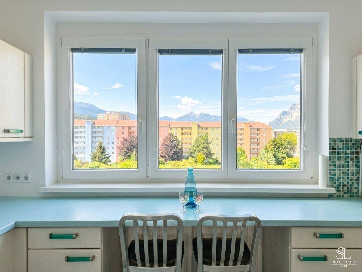 Küchenbereich mit Arbeitsplatte, Sitzgelegenheiten und Panoramablick auf die Berge und Stadt.