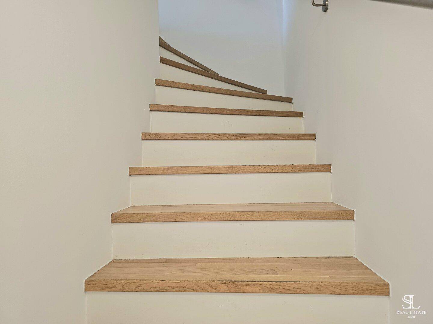 Moderne Treppe mit Holzstufen und weiß gestrichenen Setzstufen, die in die obere Etage führt.