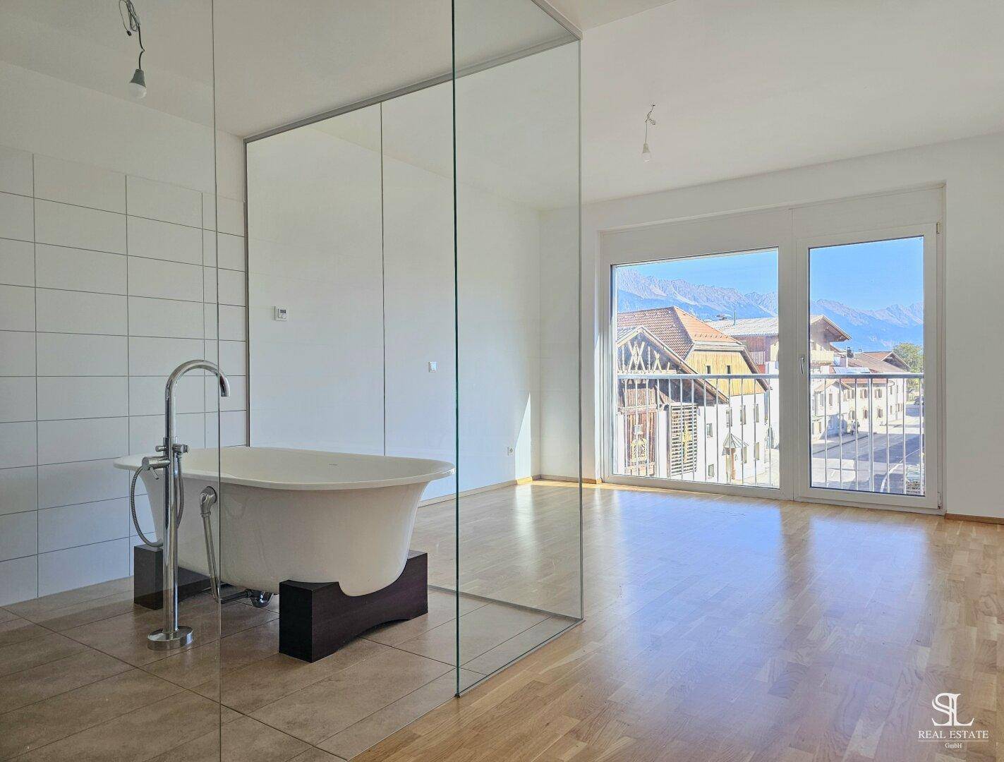 Helles Badezimmer mit freistehender Badewanne und großem Fenster mit Bergblick.