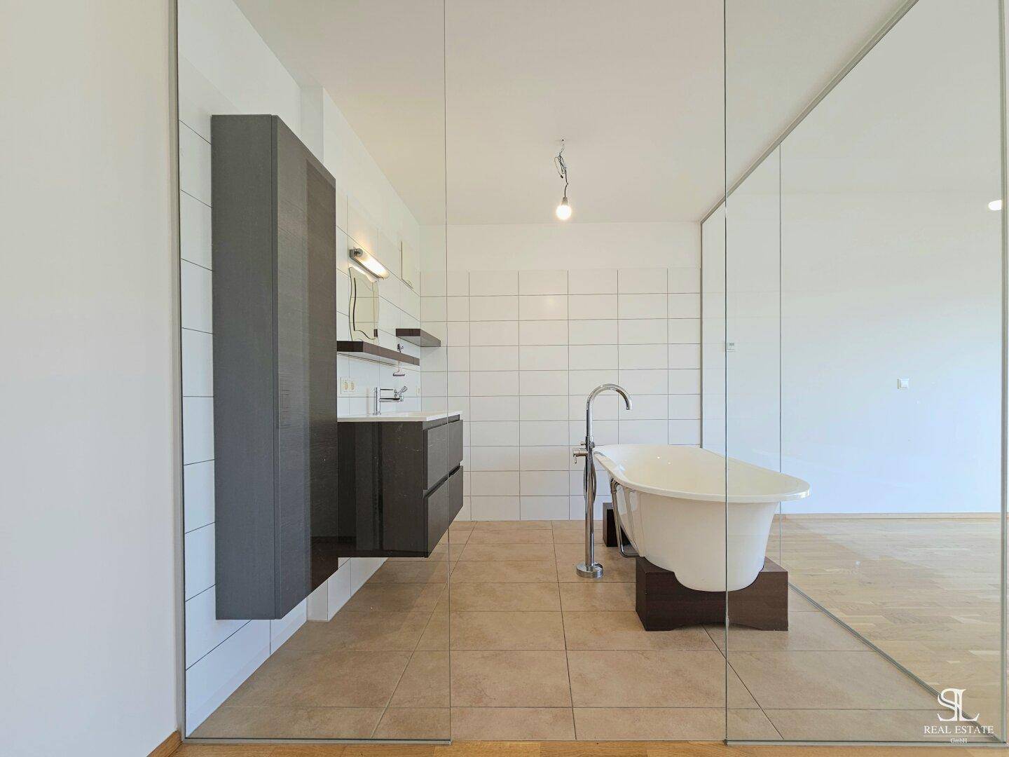 Modernes Badezimmer mit Waschtisch, Spiegel und freistehender Badewanne in einer Glasdusche.