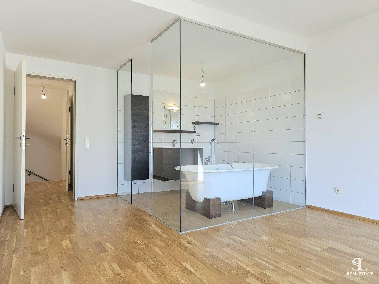 Geräumiges Badezimmer mit freistehender Badewanne, Waschtisch und Holzboden.
