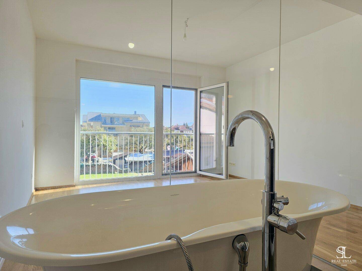 Blick aus der Badewanne durch ein großes Fenster auf die umliegende Wohngegend.