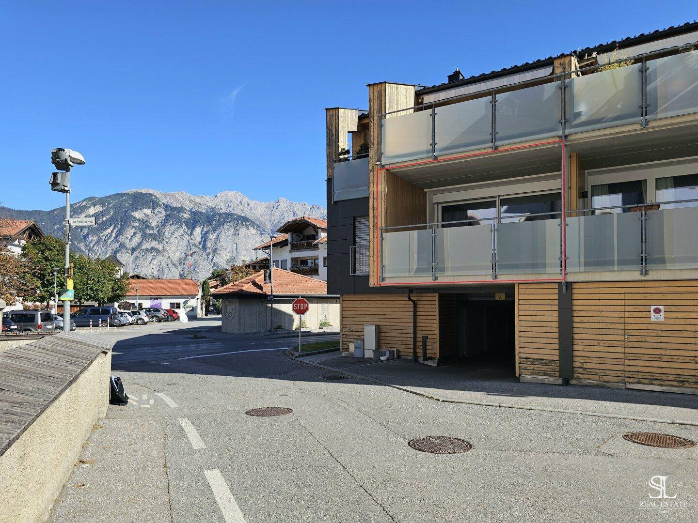 Gebäudeansicht mit modernen Balkonen und Glasgeländern, umgeben von einer Berglandschaft.