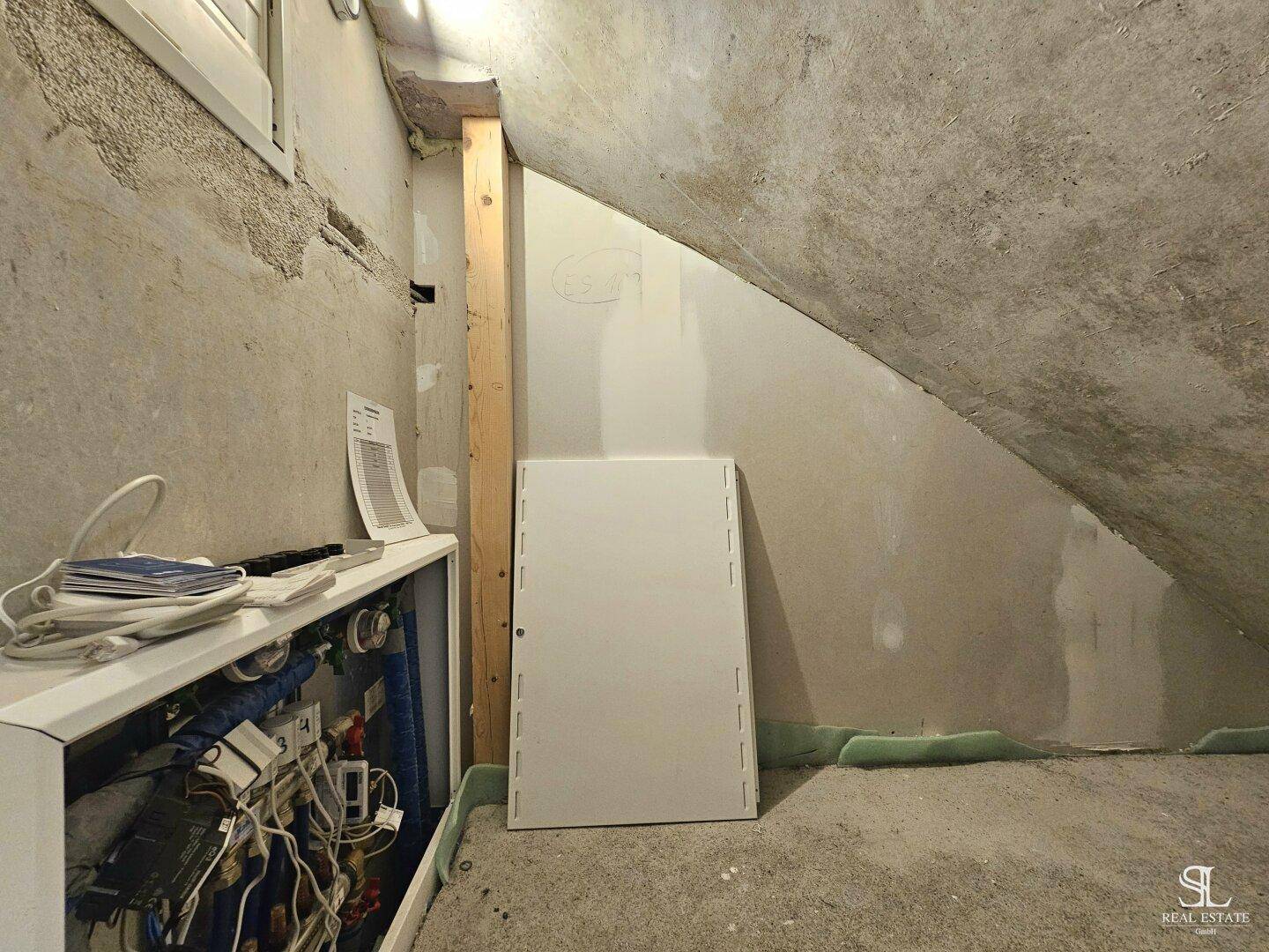 Unausgebauter Dachbodenbereich mit schrägen Wänden und sichtbaren Installationen, bietet Ausbaupotenzial.