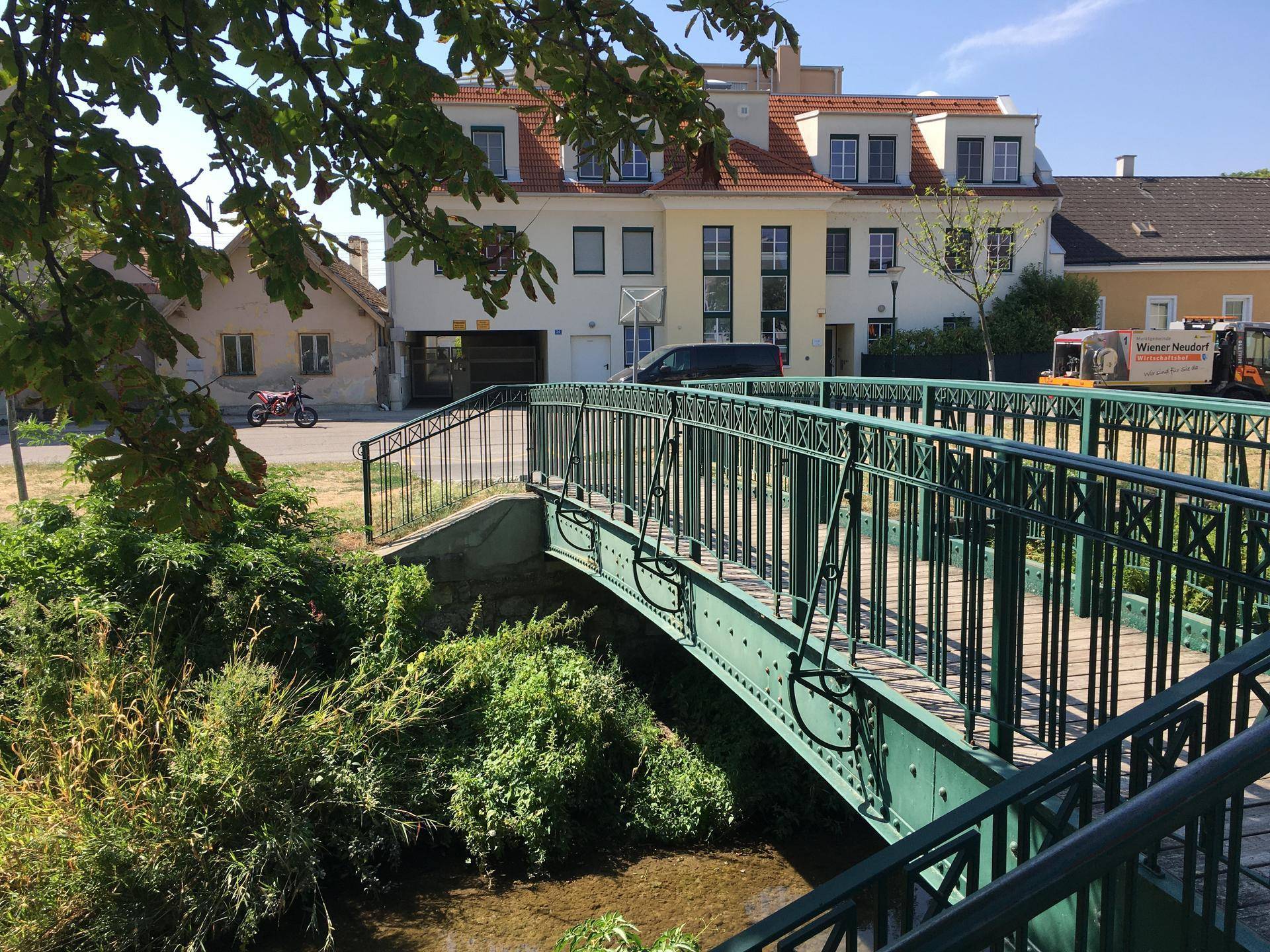 Ansicht eines Wohngebäudes in ländlicher Umgebung mit einer kleinen Brücke.